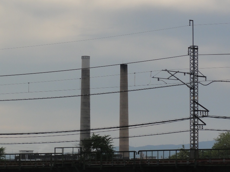 JR奈良線の背景にそびえ立つ二本の煙突